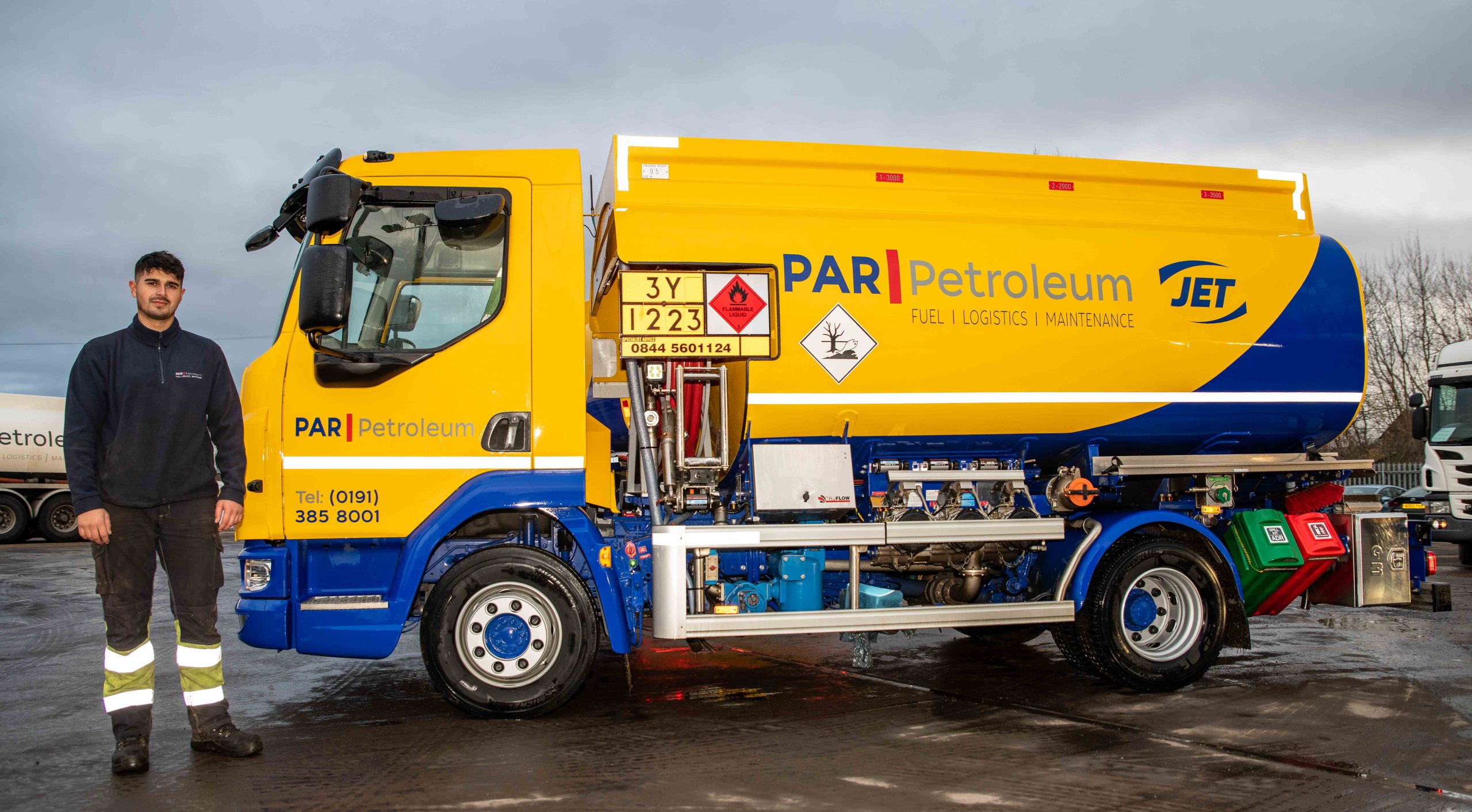 A man stands next to a large yellow and blue vehicle with the words Par Petroleum along the side