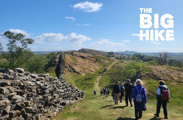 A section of Hadrian's Wall in Northumberland, people walking alongside it.