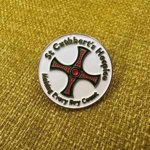 White pin badge with St Cuthbert's Cross in the centre. Around the outside text says: St Cuthbert's Hospice Making Every Day Count.