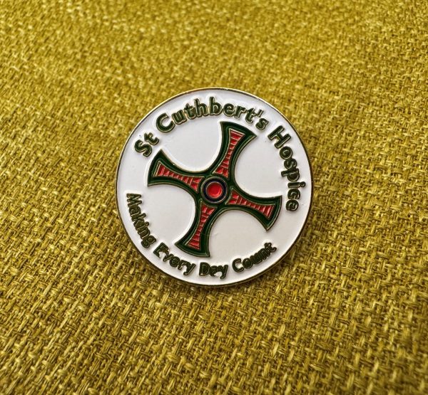 White pin badge with St Cuthbert's Cross in the centre. Around the outside text says: St Cuthbert's Hospice Making Every Day Count.