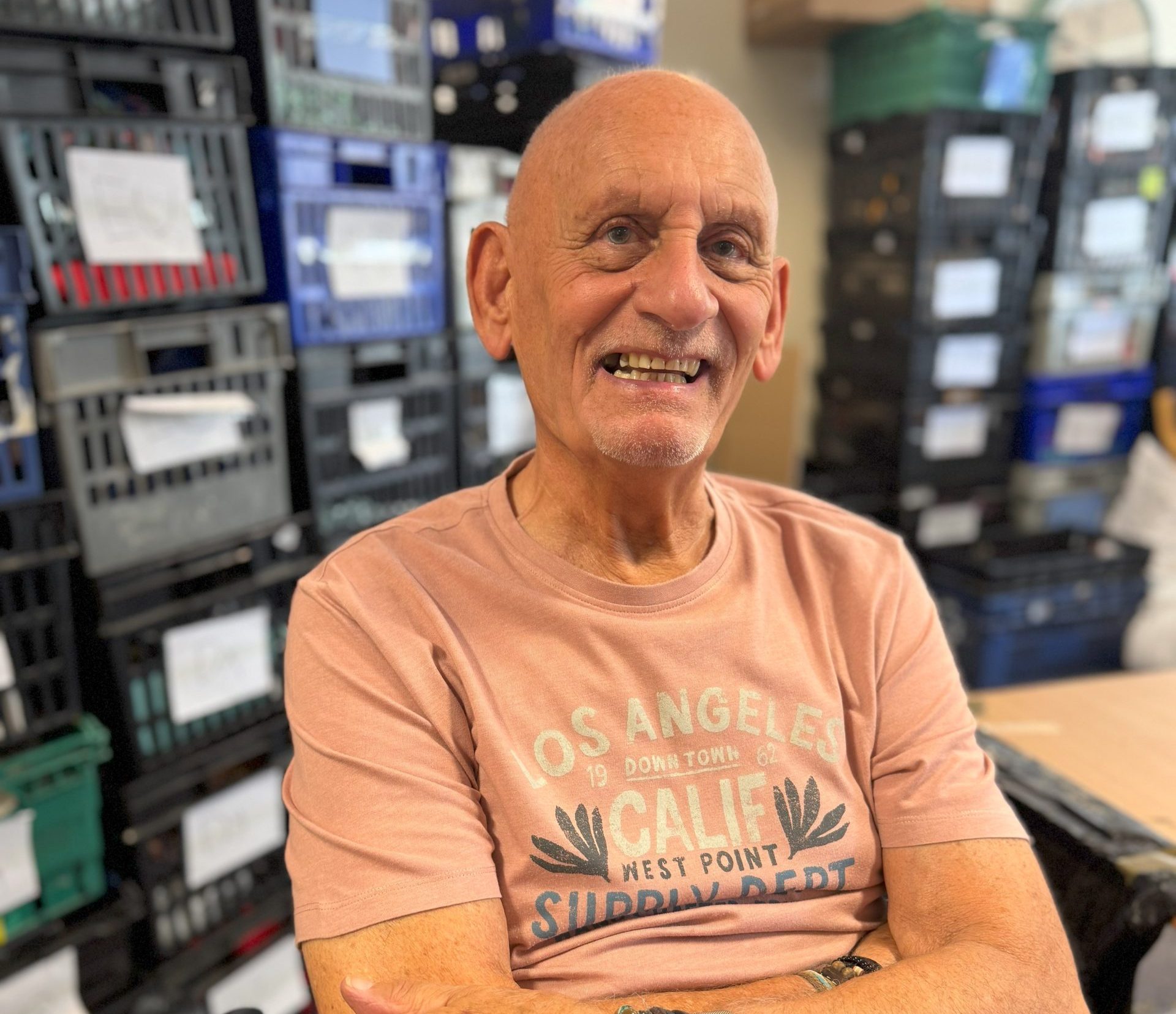 A man sitting in a chair with his arms crossed, looking relaxed and smiling.