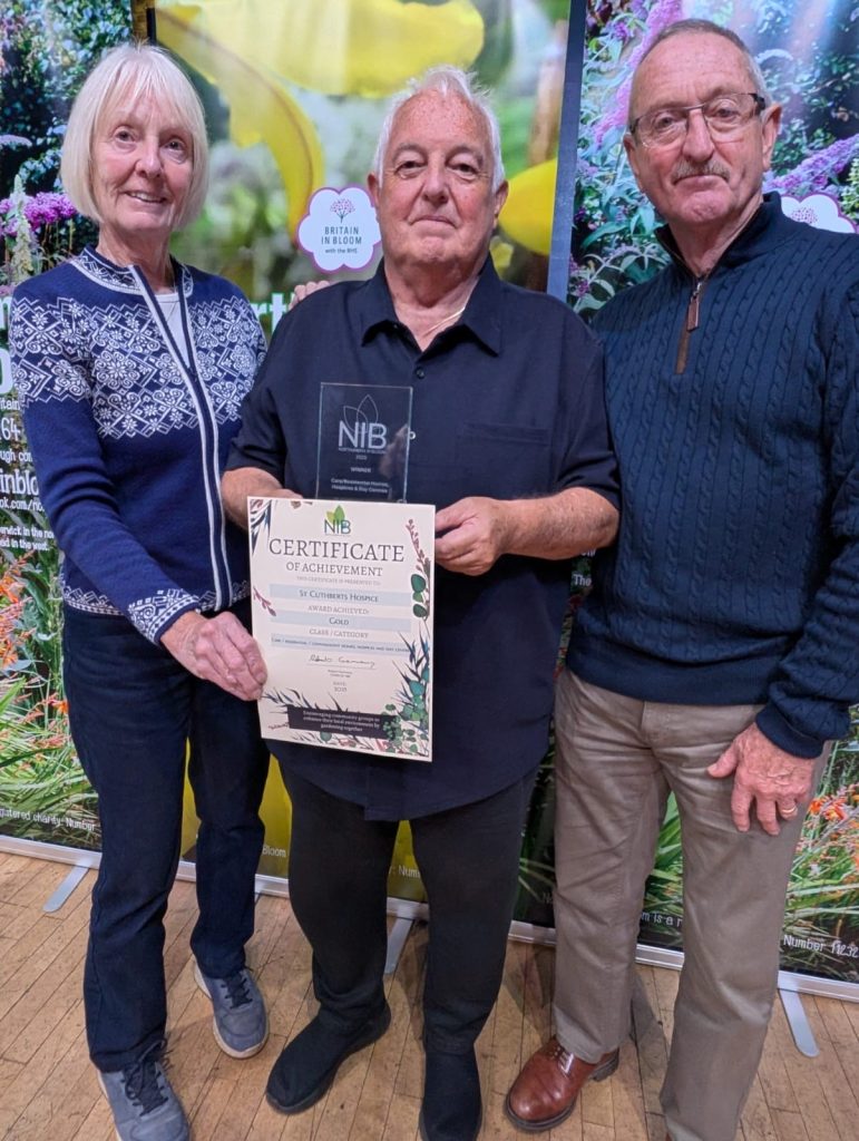 Three people proudly holding a certificate and award